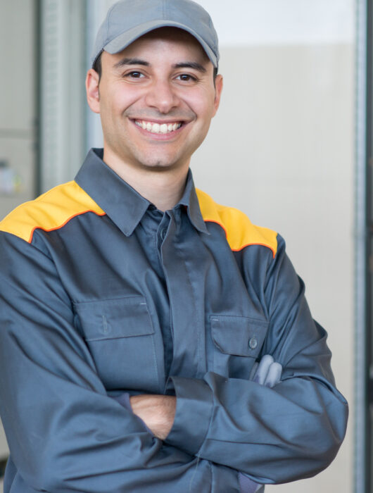 Portrait of a smiling electrician in front of an industrial electric panel in a factory Portrait of a smiling electrician in front of an industrial electric panel in a factory